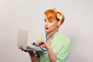 Surprised pinup girl listening computer with stethoscope