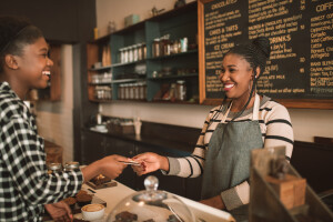 Smiling woman giving her credit card to a cafe barista